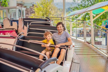 Mutlu gülümseyen oğlu ve yakışıklı babası lunaparkta birlikte eğleniyorlar.