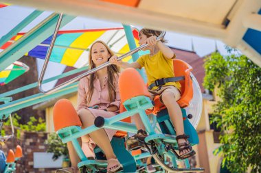 Gülümseyen oğluyla annesi lunaparkta birlikte vakit geçiriyorlar.
