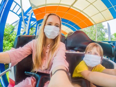 Bir lunaparkta COVID-19 Coronavirüs sırasında tıbbi maske takan bir aile.