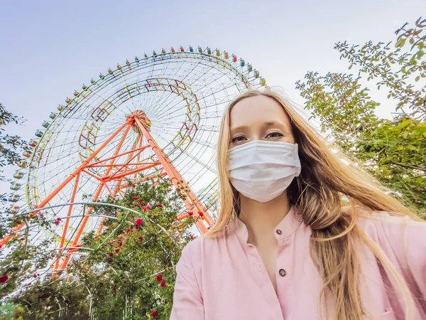 A woman in a pink dress takes a selfie on the background of a ferris wheel — Stock Photo, Image