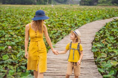Anne ve oğlu, Lotus Gölü 'nün yanındaki yolda sarı bir yolda. Mua Mağarası, Ninh Binh, Vietnam. Vietnam, Coronovirus COVID 19 konseptinden sonra yeniden açıldı.
