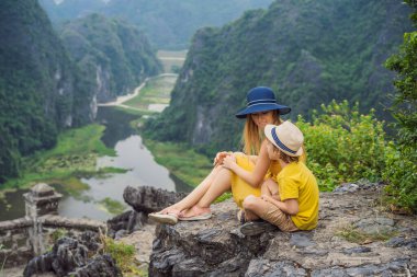 Anne ve oğul turistler Tam Coc gölünde ve Hang Mua Tapınağı, Ninh Binh, Vietnam. UNESCO Dünya Mirası Alanı 'dır ve tekne mağarası turlarıyla ünlüdür. Vietnam topraklarındaki Halong Körfezi.