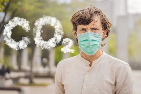 Men wearing facial hygienic mask for Safety outdoor. CO2 lettering made of clouds. Sky with CO2 pollution, smog People in masks because of fine dust. Problems found in major cities around the world — 스톡 사진