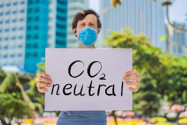Mannen i medicinsk mask innehar en affisch Lettering text CO2 Neutral — Stockfoto