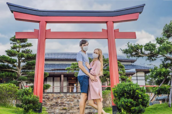 의료용 마스크를 쓴 행복 한 커플 이 일본 전통 건물을 보고 있습니다. 코로나 바이러스가 유행 한 이후 관광객들 이 일본으로 여행하다 — 스톡 사진