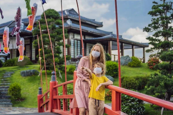 의료 마스크를 쓴 어머니와 아들 이 일본의 전통적 인 건물을 보고 있습니다. 코로나 바이러스가 유행 한 이후 관광객들 이 일본으로 여행하다 — 스톡 사진