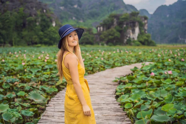 Jovem em um vestido amarelo no caminho entre o lago de lótus. Mua Cave, Ninh Binh, Vietname. Vietname reabre após quarentena Coronovirus COVID 19 conceito — Fotografia de Stock