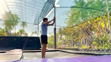 Yavaş çekim yap. Genç bir adam tropik bölgelerdeki trambolin parkında eğleniyor. Telefonla vurulmuş.