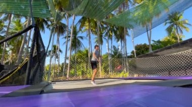 Yavaş çekim yap. Genç bir adam trambolin parkında eğleniyor. Telefonla vurulmuş.