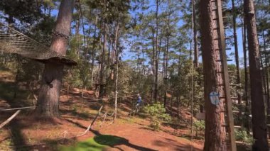 Sarı kasklı bir çocuğun yavaş çekim halat tırmanışı parkında eğlenirken. Telefonla vurulmuş.