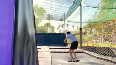 Yavaş çekim yap. Genç bir adam tropik bölgelerdeki trambolin parkında eğleniyor. Telefonla vurulmuş.