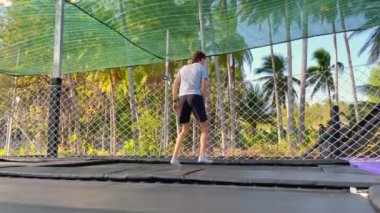 Yavaş çekim yap. Genç bir adam tropik bölgelerdeki trambolin parkında eğleniyor. Telefonla vurulmuş.