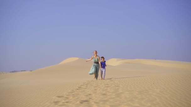 Syuting lambat dari seorang wanita muda dan anak kecil bersenang-senang di padang pasir — Stok Video