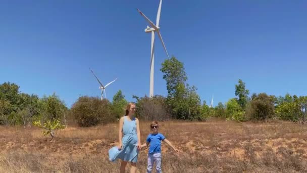 Disparo en cámara lenta. La joven y su hijo visitan un parque eólico en un entorno semidesértico. Concepto de energía eólica — Vídeos de Stock