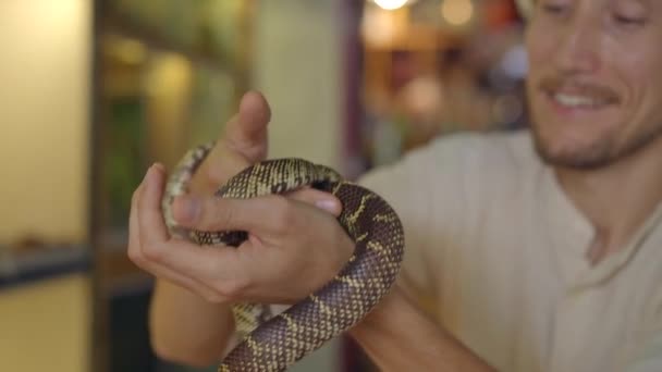Un hombre visita un café con animales exóticos. Café donde se puede contactar con animales. Está tocando una serpiente.. — Vídeos de Stock