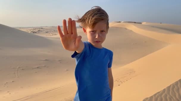 Spowolniony ujęcie małego chłopca stojącego na pustyni, który trzyma otwartą dłoń przed nim jako znak stopu. Zmniejszenie emisji dwutlenku węgla. Zatrzymanie zmian klimatu — Wideo stockowe