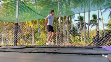 Yavaş çekim yap. Genç bir adam tropik bölgelerdeki trambolin parkında eğleniyor. Telefonla vurulmuş.