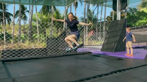 Slowmotion shot. A young woman is having fun in a trampoline park in tropics. Shot on a phone — Stock Video