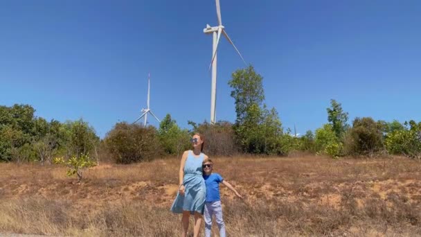 Tir au ralenti. Une jeune femme et son fils visitent un parc d'éoliennes dans un environnement semi-désertique. Concept d'énergie éolienne — Video