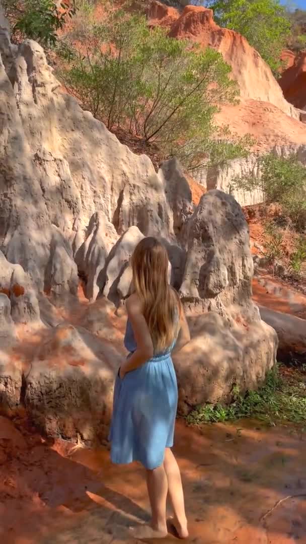 Vertical video. Slowmotion shot. A woman tourist is visiting the red canyon or Fairy stream at the border of desert in the Mui Ne village in southern Vietnam. Shot on a phone — Stock Video