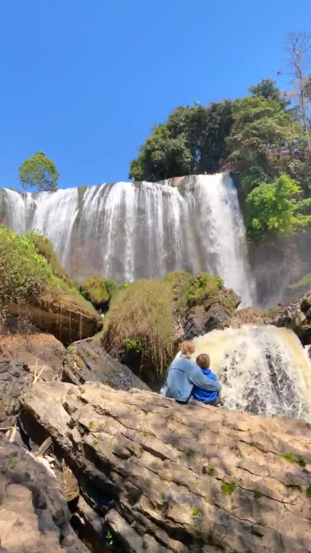 Vidéo verticale. Tir au ralenti. Famille de touristes visite la cascade de l'éléphant dans la ville de Dalat dans la partie sud du Vietnam. Voyage au Vietnam concept — Video