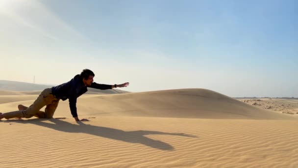 Un hombre en un paño de oficina se arrastra hasta una duna en un desierto. Superar los retos en las empresas — Vídeos de Stock