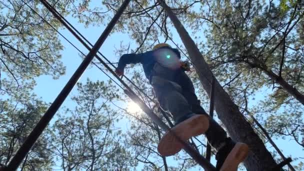 一个戴着黄色头盔的男孩在爬绳索探险公园里玩得开心的慢镜头 — 图库视频影像