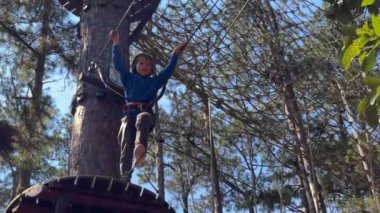 Sarı kasklı bir çocuğun yavaş çekim halat tırmanışı parkında eğlenirken. Telefonla vurulmuş.