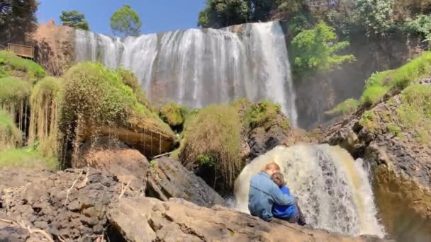 Strzał w zwolnionym tempie. Rodzina turystów odwiedza wodospad Słoń w mieście Dalat w południowej części Wietnamu. Podróż do Wietnamu. Strzał z telefonu. — Wideo stockowe