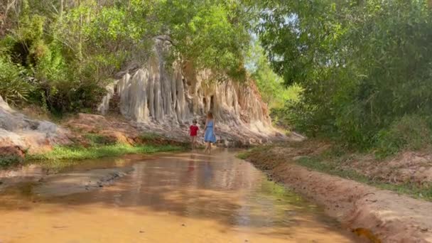 Zeitlupenschuss. Eine Familie spaziert im Dorf Mui Ne im Süden Vietnams an einem roten Canyon oder Feenbach am Rande der Wüste entlang. Schuss auf ein Handy — Stockvideo