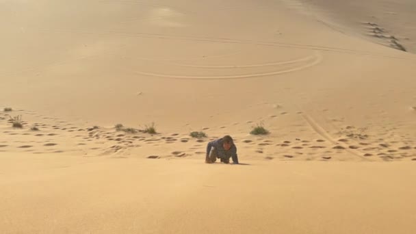 Un homme en tissu de bureau rampe dans une dune dans un désert. Relever les défis des entreprises — Video