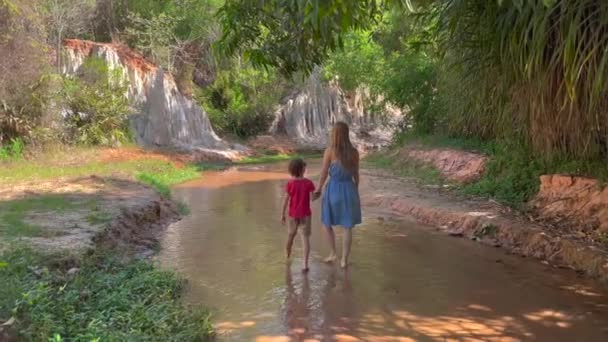 Zeitlupenschuss. Eine Familie spaziert im Dorf Mui Ne im Süden Vietnams an einem roten Canyon oder Feenbach am Rande der Wüste entlang. Schuss auf ein Handy — Stockvideo