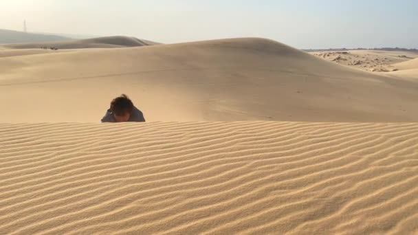 Een man in een kantoordoek kruipt in een duin in een woestijn. Uitdagingen in het bedrijfsleven overwinnen — Stockvideo