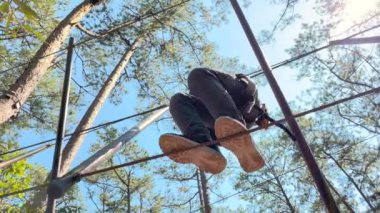 Sarı kasklı bir çocuğun yavaş çekim halat tırmanışı parkında eğlenirken.