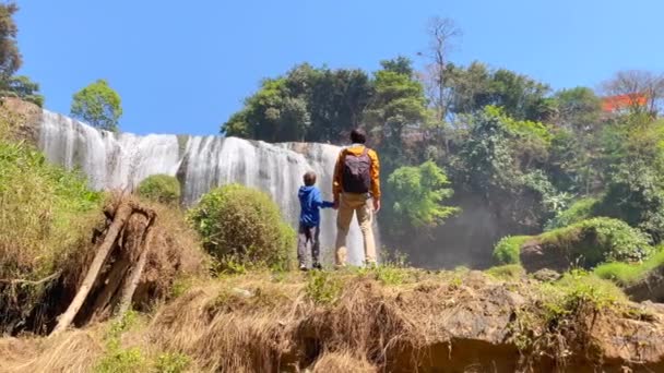 Disparo en cámara lenta. Familia de turistas visita la cascada del elefante en la ciudad de Dalat en la parte sur de Vietnam. Viajar al concepto de Vietnam. Disparo en un teléfono — Vídeo de stock