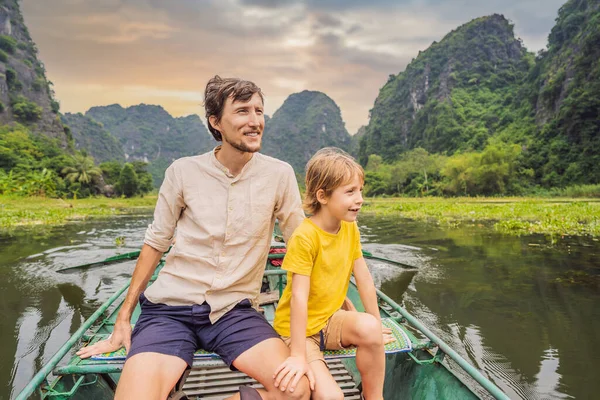 Dad and son tourists in boat on the lake Tam Coc, Ninh Binh, Viet nam. Its is UNESCO World Heritage Site, renowned for its boat cave tours. Its Halong Bay on land of Vietnam. Vietnam reopens borders — Stock Photo, Image