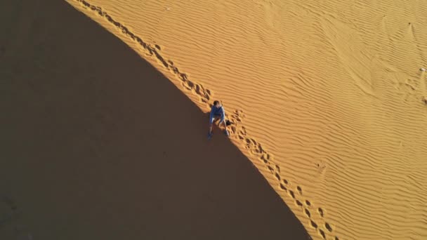 사막 모래 언덕에 앉아 있는 사람을 공중에서 찍은 장면 — 비디오