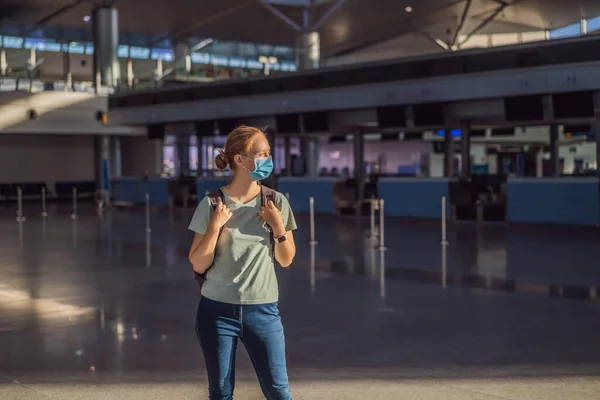 Maskierte Frau am leeren Flughafen beim Check-in in Coronavirus-Quarantäne-Isolation, Heimkehr, Flugausfall, weltweite Ausbreitung der Pandemie, Reisebeschränkungen und Grenzschließung — Stockfoto