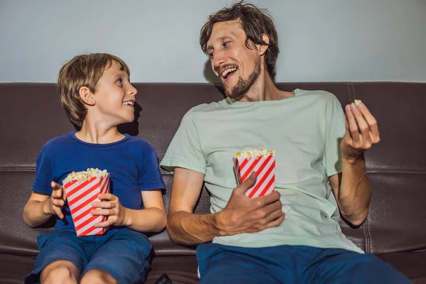 Far och son tittar på TV och äter popcort på kvällen hemma — Stockfoto