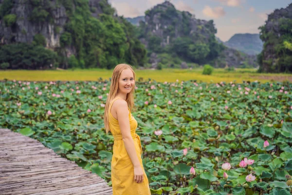 Junge Frau in gelbem Kleid auf dem Weg zwischen dem Lotussee. Mua Cave, Ninh Binh, Vietnam. Vietnam öffnet nach Quarantäne-Coronovirus COVID 19-Konzept wieder — Stockfoto