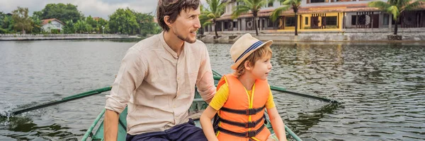 バンナー、ロングフォーマット湖タム・コック、ニンビン、ベトナムのボートで父と息子の観光客。ボートの洞窟ツアーで有名なユネスコの世界遺産です。ベトナムの土地にあるハロン湾 — ストック写真