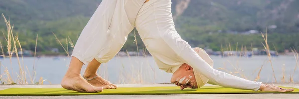 BANNER, LONG FORMAT Kundalini Yoga Frau in weißer Kleidung und Turban praktiziert Yoga Kundalini vor dem Hintergrund des Meeres, der Berge und des Sonnenuntergangs. Kämpferisches Kinderschminken der Indianer zeigt ihr Inneres — Stockfoto