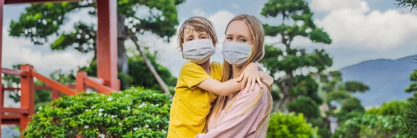 Viajeros de madre e hijo en máscara médica mirando el edificio tradicional japonés. Los turistas viajan a Japón después de la epidemia de coronavirus BANNER, FORMATO LARGO —  Fotos de Stock