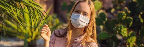 BANNER, LONG FORMAT beautiful stylish young woman in pink dress in desert among the cacti, wearing a medical mask during COVID-19 coronavirus, traveling in Africa on safari, exploring nature, sunny — Stock Photo, Image