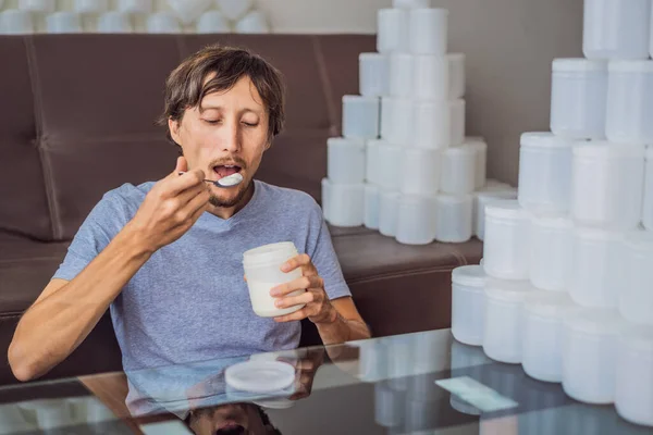 The man eats yogurt and is surrounded by many jars of yoghurt that he uses in a year. A huge amount of plastic food jars. Excessive consumption of plastic. Reduce, reuse, recycle — Stock Photo, Image