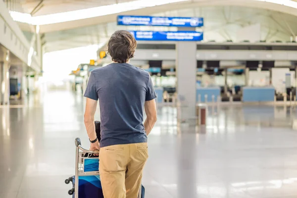 Maskierter Mann am leeren Flughafen beim Check-in in Coronavirus-Quarantäne-Isolation, Heimkehr, Flugausfall, weltweite Ausbreitung der Pandemie, Reisebeschränkungen und Grenzschließung — Stockfoto