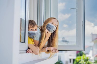 Son derece yorgun anne ve oğlu pencereden dışarı bakıyor, evde yalnız. Evde kendini izole etme, salgın COVID 19 yüzünden karantina. Evde kendini izole etme, karantina, izolasyon gibi zihinsel sağlık sorunları