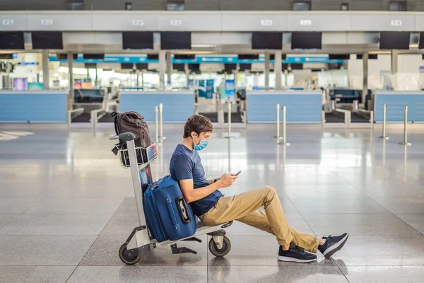 Maskierter Mann am leeren Flughafen beim Check-in in Coronavirus-Quarantäne-Isolation, Heimkehr, Flugausfall, weltweite Ausbreitung der Pandemie, Reisebeschränkungen und Grenzschließung — Stockfoto