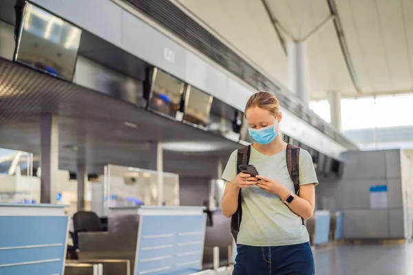 Женщина в маске в пустом аэропорту при регистрации в коронавирусной карантинной изоляции, возвращение домой, аннулирование рейсов, распространение пандемии по всему миру, ограничения на поездки и закрытие границ — стоковое фото