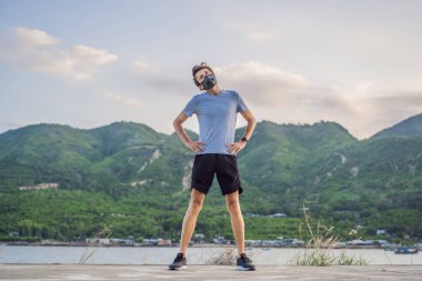 Tıbbi maske takan bir kaçakçı, Coronavirüs salgını Covid-19. Spor, karantinada aktif yaşam yüz maskesi korumalı cerrahi sterilizasyon. Corona Salgını 'nda atletizm pistinde açık hava koşusu